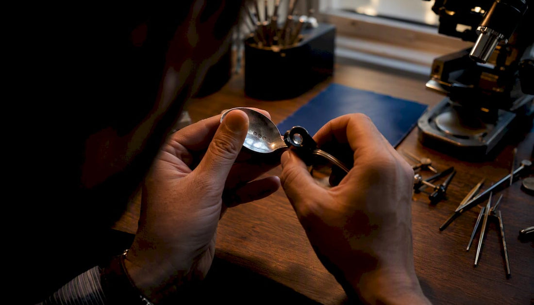 Close-up of hands inspecting silver hallmark